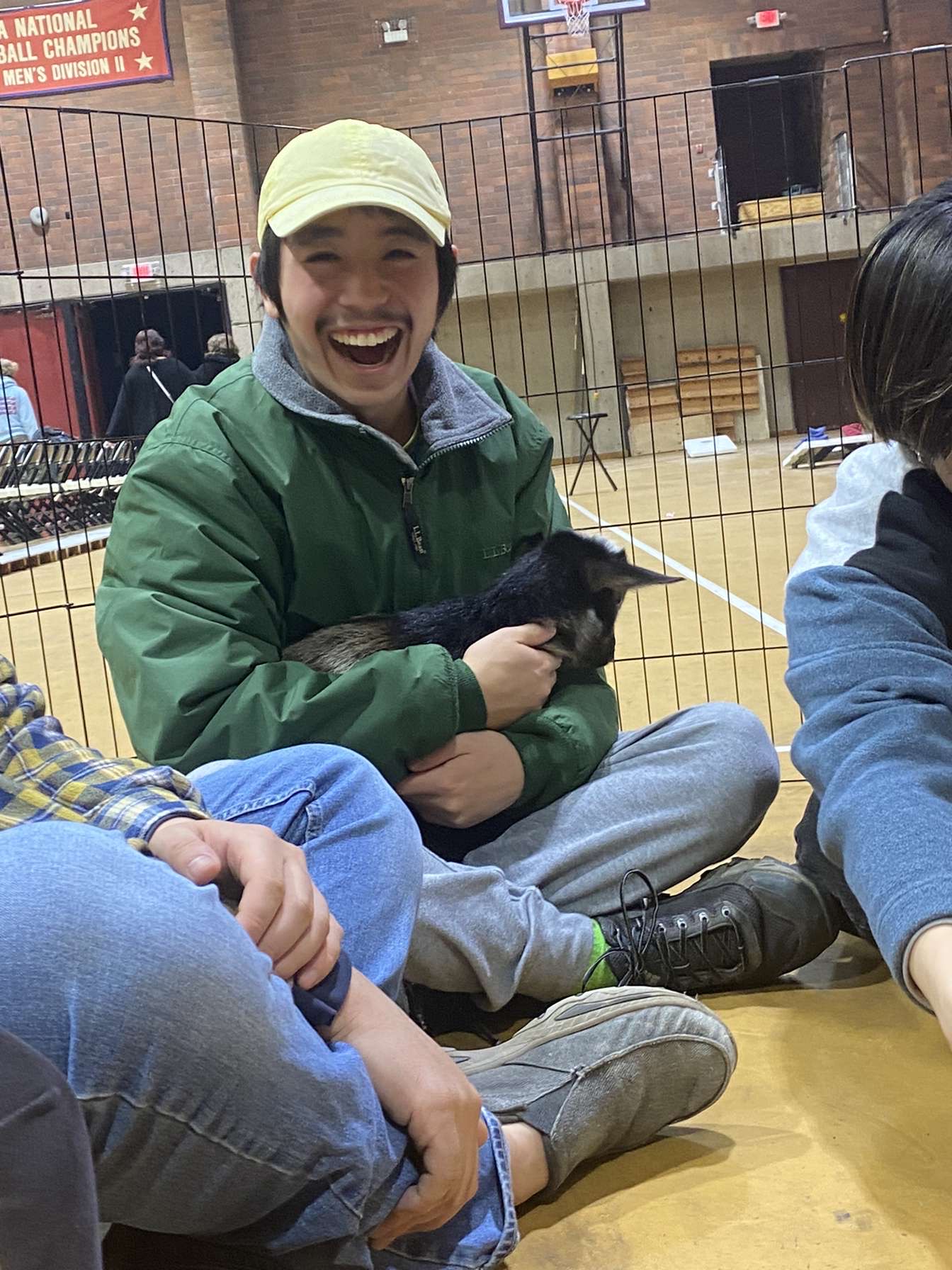 A cute looking dude holding a baby goat